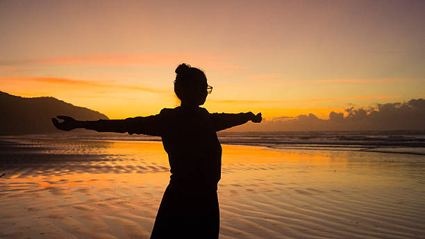 istock Silhouette Stretching on Beach at Sunrise with Orange Sky 2216720023