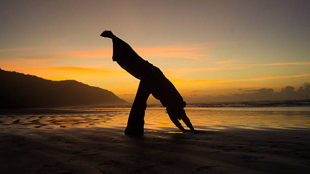 istock Silhouette Stretching on Beach at Sunrise with Orange Sky 2216720088