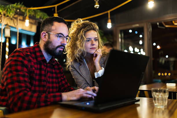 istock Focused coworkers collaborating on a laptop in a stylish, modern workspace during evening hours, surrounded by ambient lighting, emphasizing teamwork, concentration, and a productive work environment for creative projects. 2216720816