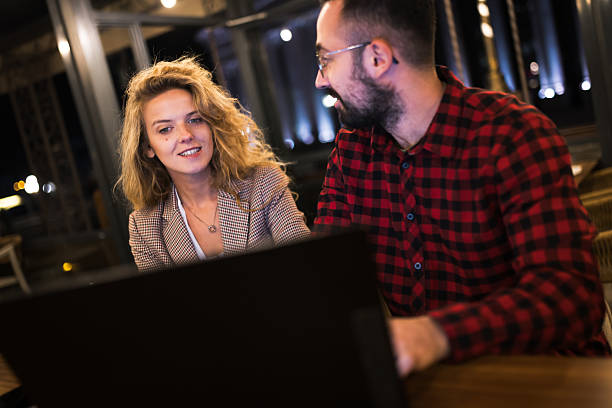 istock Young professionals collaborating on laptop during evening in modern office with smile and concentration 2216720913