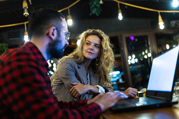 istock Two colleagues discussing project ideas at a cozy cafe with warm lighting and vintage decor, focusing on a laptop screen displaying important business information during a productive evening brainstorming session. 2216720936