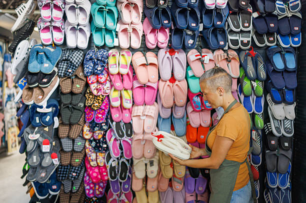 Outdoor market scene where a woman selling soft, comfortable slippers, rear view