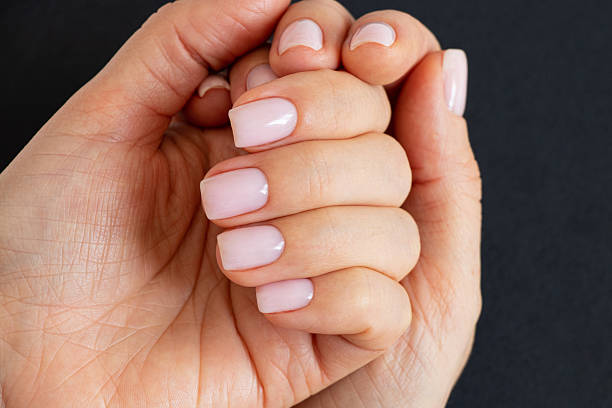 istock Women's hands with a delicate light manicure on a black background, hand 2216724516