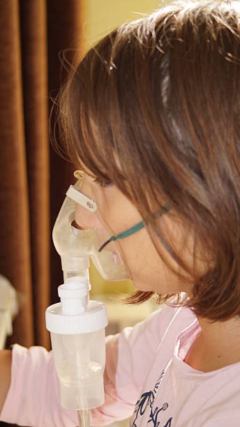 istock girl making inhalation with nebulizer 2216729009