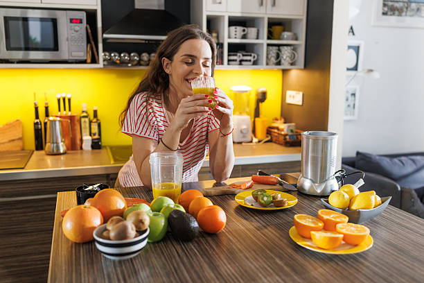 istock Woman enjoying fresh orange juice in a bright modern kitchen setting 2216730610