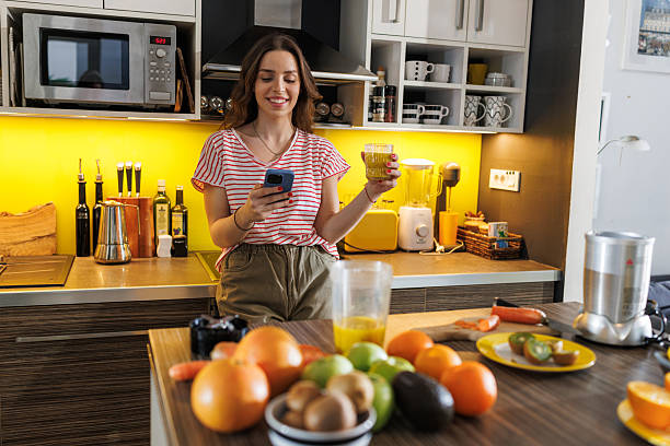 istock Woman enjoying fresh juice while checking phone in modern kitchen 2216730622