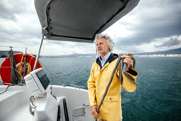 A senior boat captain focused on managing a rope aboard his vessel. The image highlights experience, skill, and hands-on work in a maritime setting.