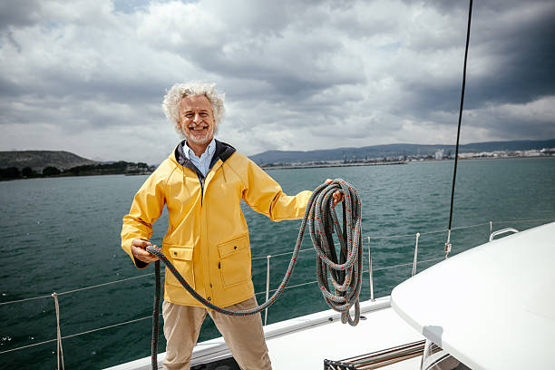 A senior boat captain holding a rope on deck while looking confidently at the camera. The image conveys experience, authority, and connection in a maritime environment.