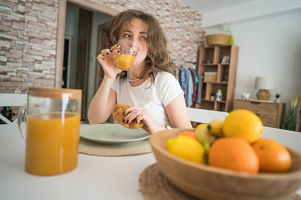 Young woman enjoying a healthy breakfast with orange juice and croissant