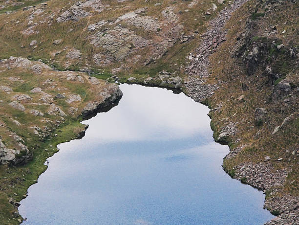 remote untouched mountain lake within rocks and reflecting the cloudy sky
