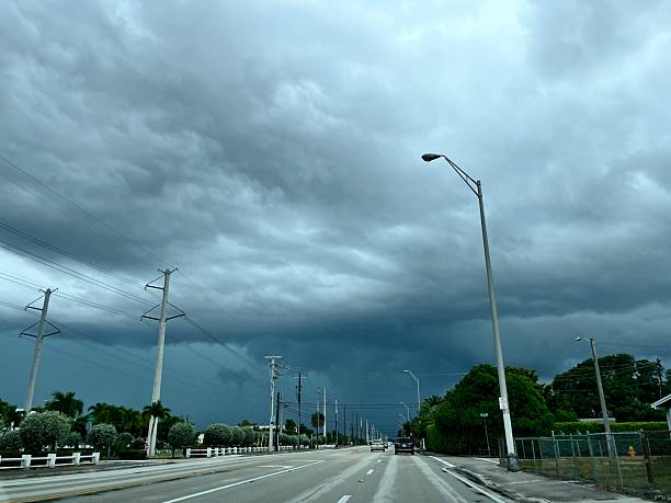 Gathering ominous dark clouds loom over a street in Miami, Florida, signaling an impending storm. The atmosphere thickens as thunderstorm conditions develop, creating a dramatic sky