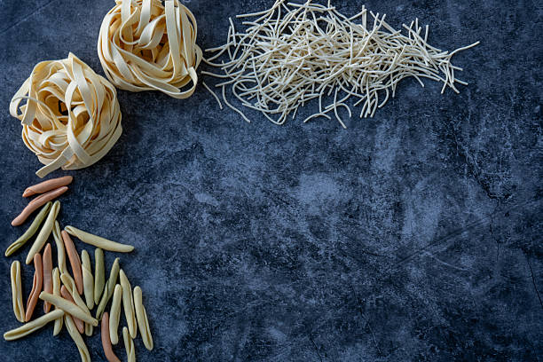 istock Various kinds of uncooked pasta on the dark kitchen counter. 2216752641