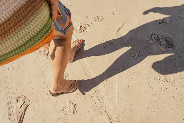 Woman walking on the beach in flip flops