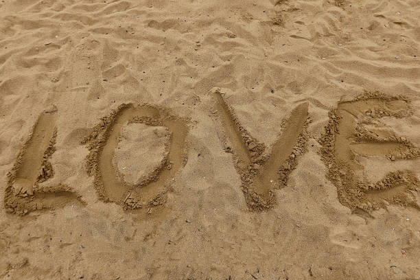 istock Word LOVE written in beach sand, top view natural background with footprints and texture, symbol of romance, simplicity, freedom, and vacation mood 2216757427