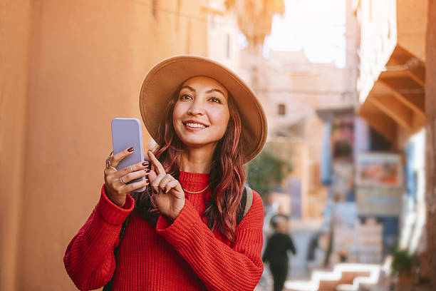 istock Young woman tourist using smartphone app and smiling while visiting Marrakech medina in Morocco 2216763179