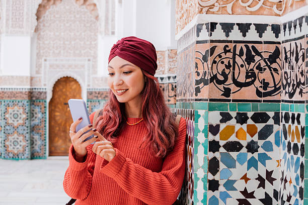 istock Young woman using smartphone in Marrakech Madrasa Ben Youssef, Morocco, exploring ancient architecture and enjoying travel experience 2216763204