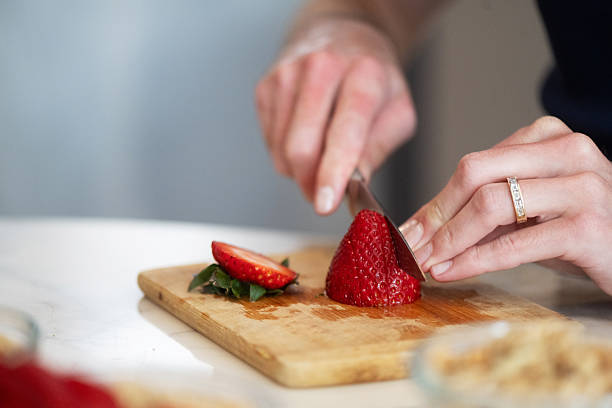 istock Close Up of Man's Hands Slicing Strawberry 2216764341