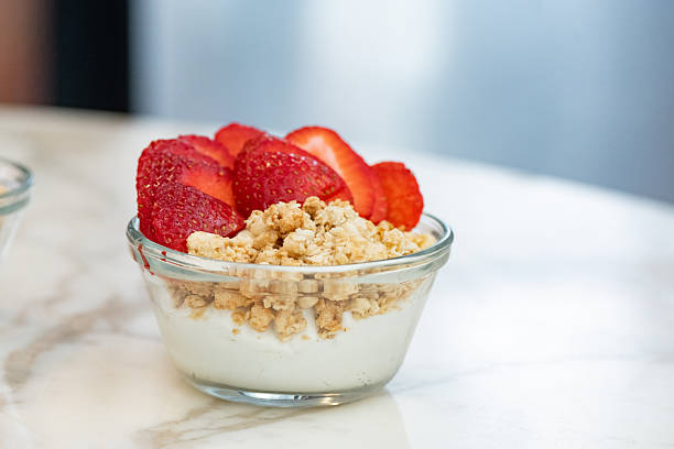 This is a photograph of a homemade yogurt parfait topped with granola and strawberries.