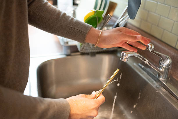 istock Hispanic Man in 30s Washes Reusable Metal Straw in Kitchen Sink 2216766158