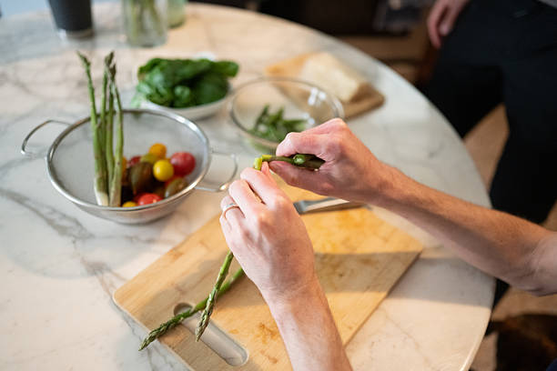 istock Millenial Man Preparing Asparagus at Kitchen Table in NYC 2216766291