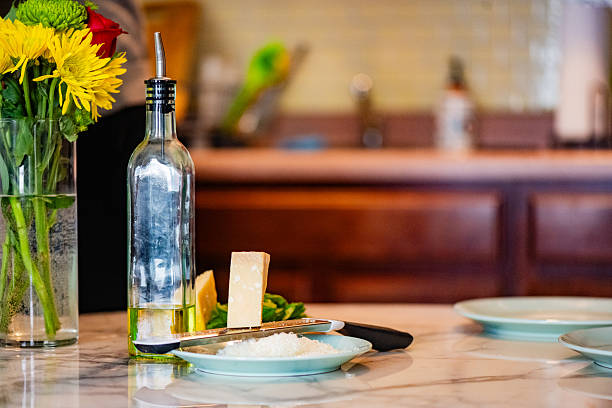 This is a still life photograph of a bottle of olive oil and grated Parmesan cheese on the table in the kitchen of a NYC apartment.