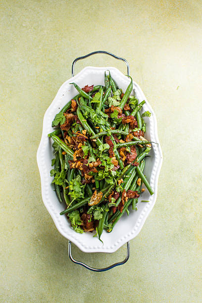 Delicious green beans salad with bacon, orange, peanuts, garlic and spices on a plate. Healthy warm salad idea.