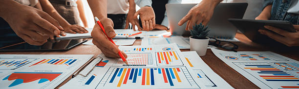 istock Focus financial report papers with blurred analyst team working. Scrutinize 2216768476