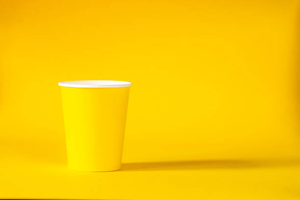 Yellow paper cup on yellow background. copy space