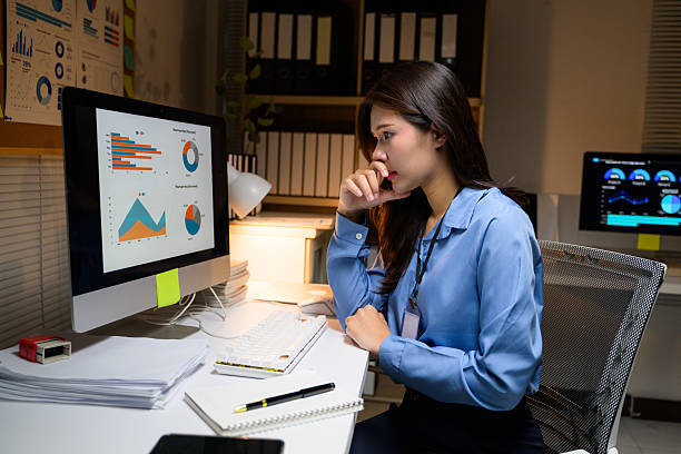 istock Young adult analyzing graphs and charts on a computer screen, focused on financial data and market trends, working late in an office environment 2216772905