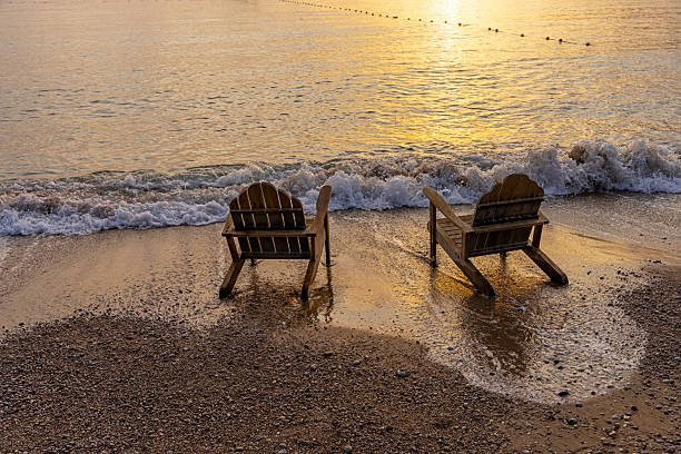 Silhouette of two deck chairs on a sandy beach at sunrise, Kemer Antalya