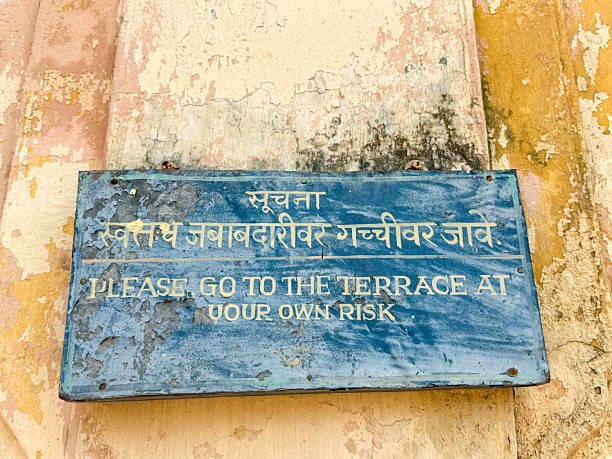 A sign on a wall that says please go to the terrace at your own risk. The sign is blue and has foreign writing on it