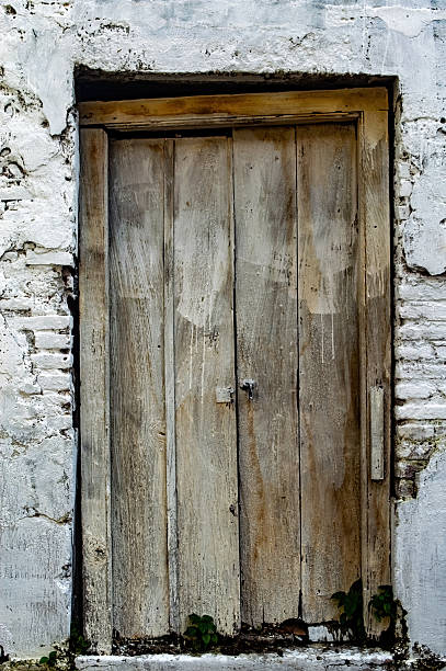 istock A rustic, weathered wooden door set in a crumbling, white washed brick wall, showcasing textures, decay, and a sense of forgotten history 2216783504