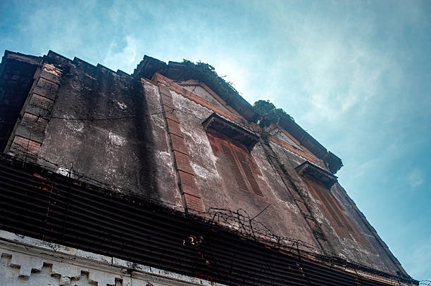 istock A dramatic low angle shot of a derelict, aged colonial building under a bright blue sky, showcasing weathered textures, vintage windows, and signs of decay 2216783505