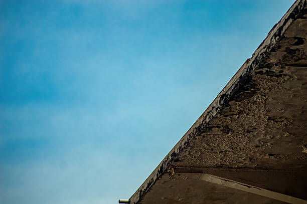 A weathered concrete ledge or rooftop against a clear blue sky, emphasizing texture and the raw, imperfect beauty of urban decay or minimalist architecture