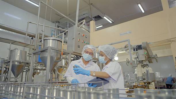 istock Two workers wearing lab coats inspecting equipment at food processing plant. Supervisor working with digital tablet check product on the conveyor belt in the canned food factory. GMP, HACCP, Manufacturing industry. 2216788267