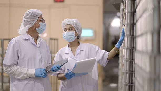 istock Team warehouse staff or quality supervisor in white sterile uniforms, inspecting product quantity or raw materials via the application on the tablet in processed food factory or manufacturing industry, discuss the development of indicators of production. 2216788278
