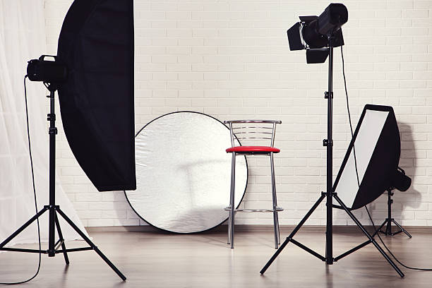istock Professional studio equipment and chair on white brick wall background 2216790882