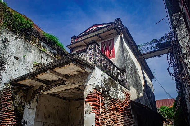 istock An old, weathered building in Indonesia with crumbling brick and peeling paint under a blue sky. Historic architecture shows age and neglect with green plants 2216792182