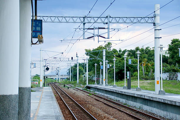 istock Taiwan May 21, 2024: A railway track curving into the distance beside a station platform, surrounded by greenery and power poles Fuli Station and Train in Taiwan 2216792263