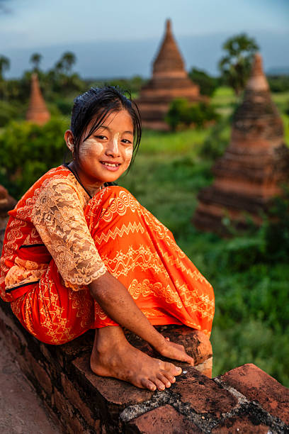 Young Burmese girl with thanaka face paint looking at an ancient temples of Bagan, Myanmar (Burma)
