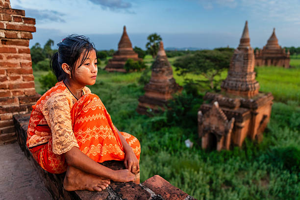 Young Burmese girl with thanaka face paint looking at an ancient temples of Bagan, Myanmar (Burma)