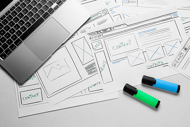 istock Developing UI design. Sketches of website wireframes, laptop and felt pens on white marble table, top view 2216798261