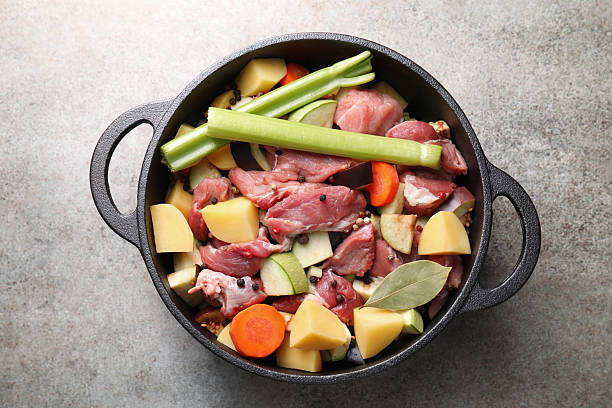 Cooking stew. Uncooked meat and vegetables in pot on light grey table, top view