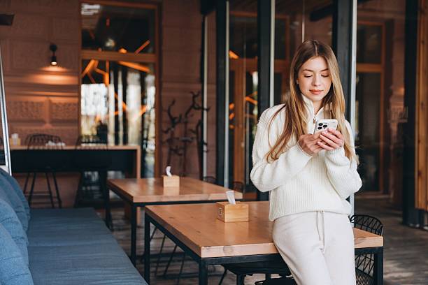 istock Young woman using mobile phone while leaning on a table in a cafe 2216799347