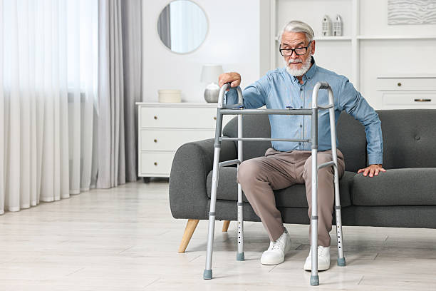istock Senior man with walking frame on sofa at home 2216799419