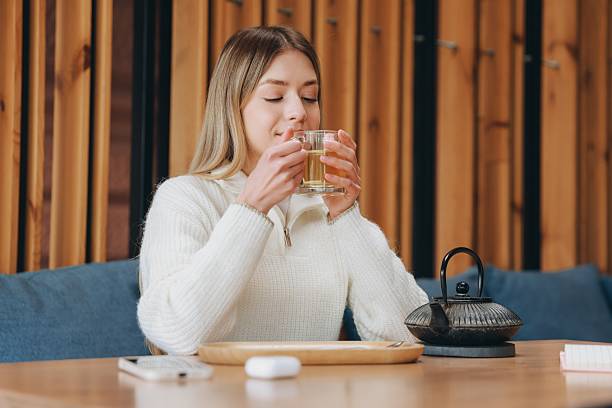 istock Young woman drinking herbal tea in a modern cafe 2216800167