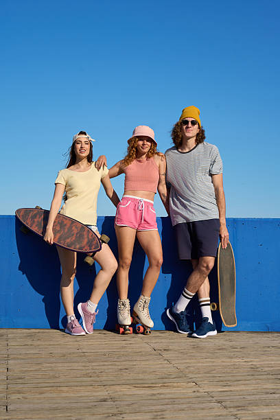 istock Young people posing with skateboards and roller skates by blue wall 2216800339