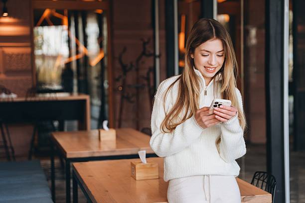 istock Young woman using mobile phone in cafe 2216801578