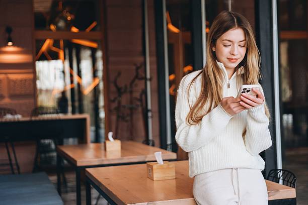 istock Young woman using mobile phone in a cafe 2216801582