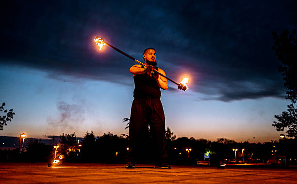 Fire performer juggling burning staff at dusk